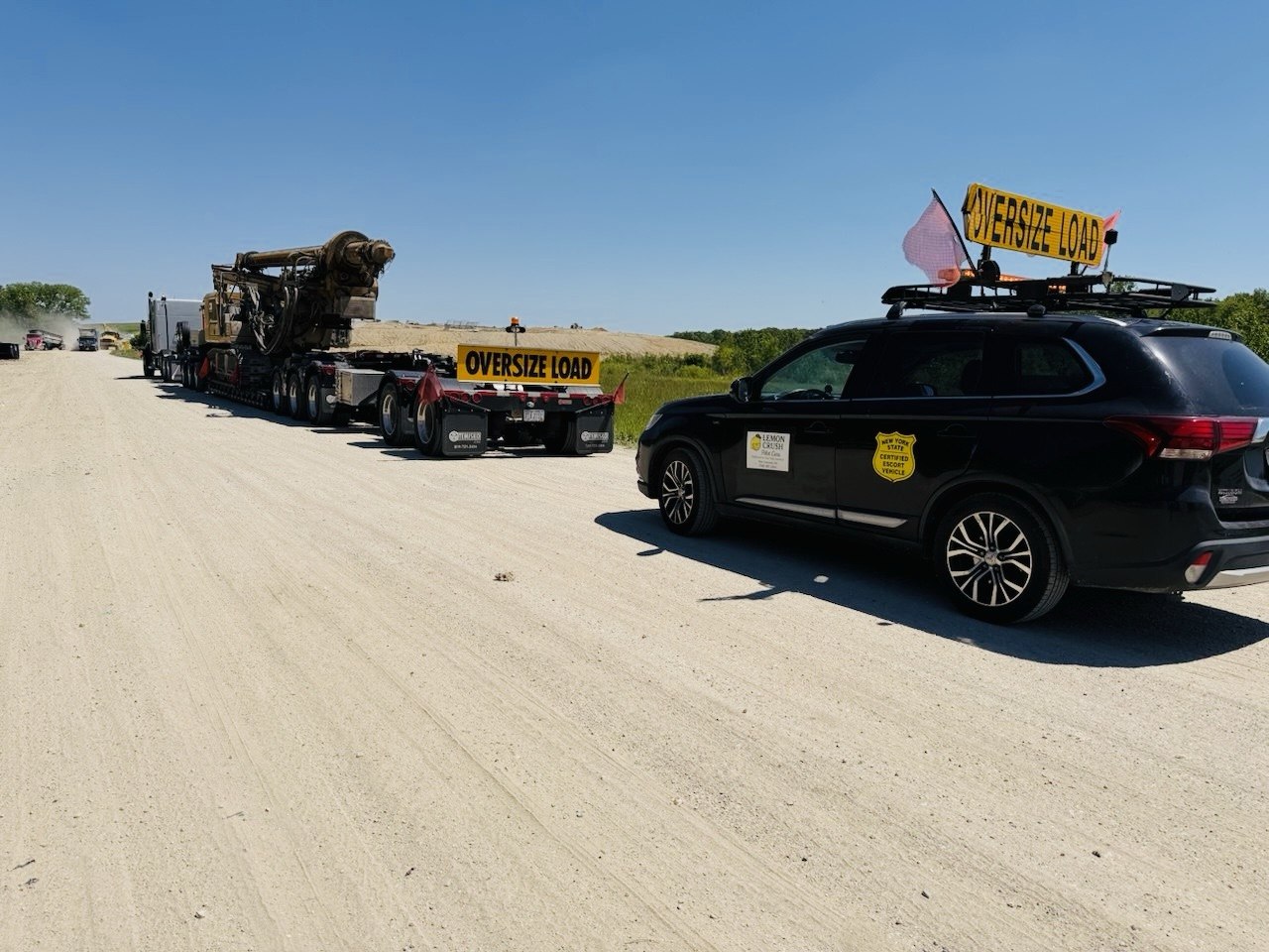 Oversized drill rig moving under escort by a certified pilot car