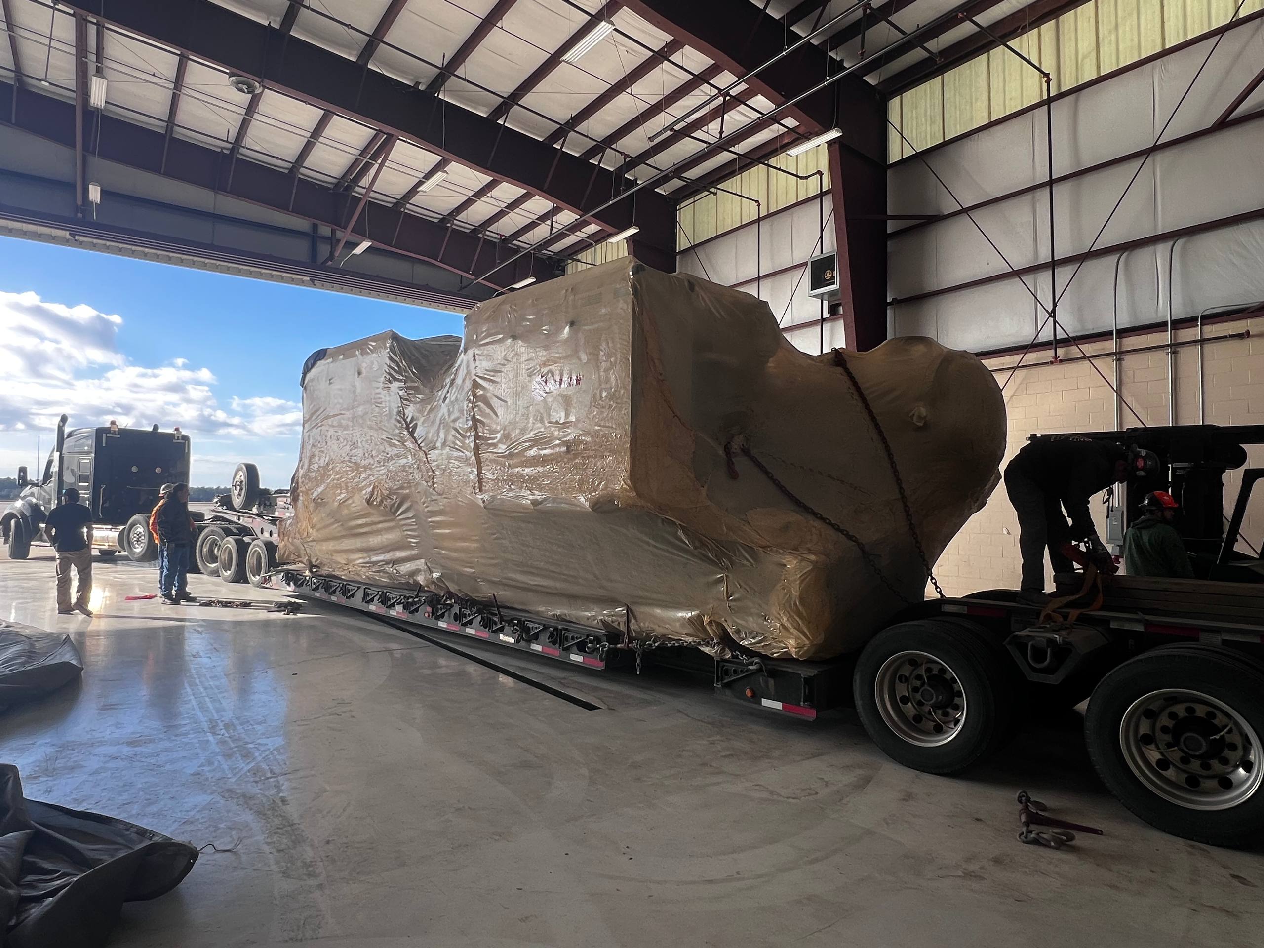 Tarped massive industrial load on RGN trailer in warehouse
